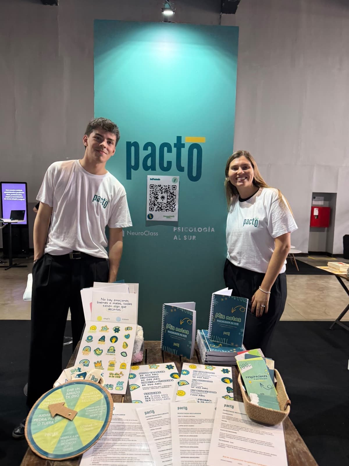 Dos integrantes de Pacto junto a su stand en el congreso Psicología al Sur